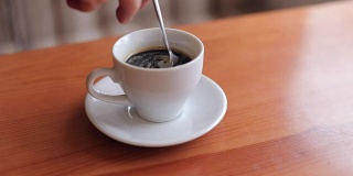 一个男人在一杯咖啡里搅拌糖。
