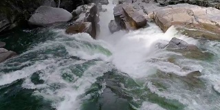 慢动作无人机低飞在绿色的水在瀑布边缘在岩石峡谷