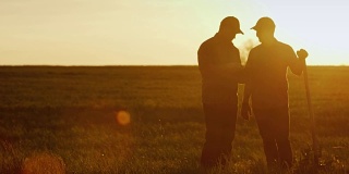 两个农民在地里聊天，用着药片。美丽的夕阳，两个男人的剪影。Copyspace组成