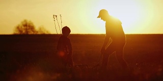 一位父亲和他的小儿子在日落时分一起种树。新生活，强大的家庭和传统