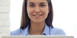 在工作中微笑快乐的女人的特写，笔记本电脑