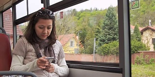 一名年轻女子在乘坐公交车时使用智能手机