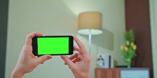 男性手持绿色屏幕的手机