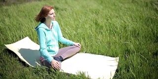 美丽的年轻女子练习瑜伽运动和姿势户外在绿色的草地