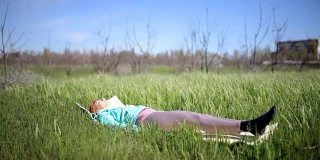 美丽的年轻女子练习瑜伽运动和姿势户外在绿色的草地
