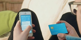 年轻男子在智能手机上填写信用卡号，为网上购物付款