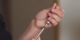 女人手里拿着注射器和胰岛素特写。