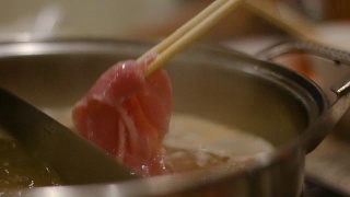 女人用筷子把滑猪肉放进火锅里的特写镜头视频素材模板下载