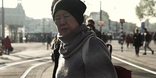 一对亚裔老年夫妇在阿姆斯特丹等电车。退休后自己环游世界