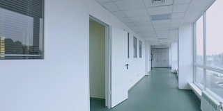医务人员在白色走廊中行走。男医生走在医院走廊上