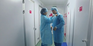 实验室工作人员穿着防护服。穿着实验室大褂的科学家们在走廊里