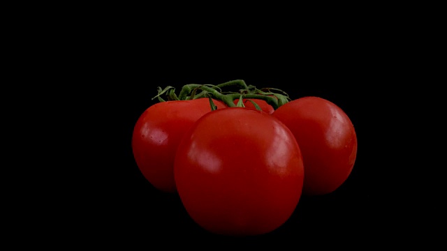 在定格动画中切开一个鲜红多汁的番茄。番茄还在藤上