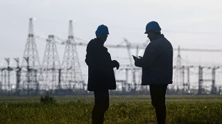 两名工程师戴着安全帽在一个能源站检查期间用智能手机聊天。视频素材模板下载