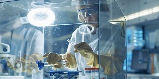 高级女科学家在隔离手套箱中处理样品。她在一个配备了最先进技术的现代实验室里。