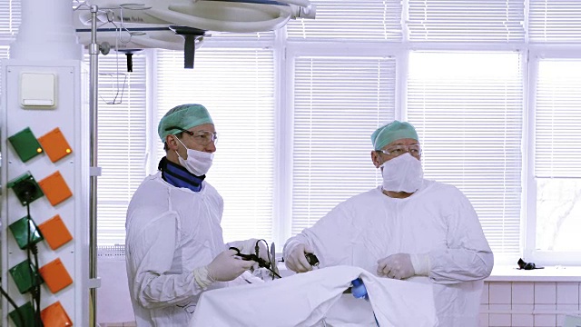 4K两名身穿医疗服、戴着口罩的医生进行腹腔镜下腹部手术。