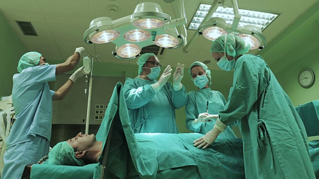 外科医生在手术室为一名男性病人进行手术时合作的团队。
