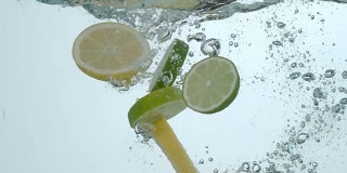 柠檬片和酸橙片在慢镜头中溅入水中
