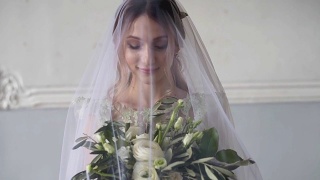 美丽的新娘在室内新娘礼服与花束和蕾丝面纱视频素材模板下载