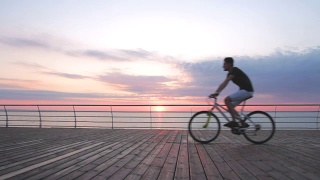 年轻人骑着山地车在海边日落或日出视频素材模板下载