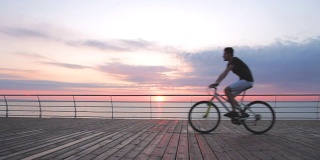 年轻人骑着山地车在海边日落或日出