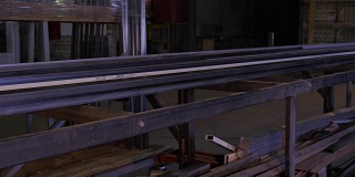 轧制钢板的轧机。倾斜变化的效果。工人将金属型材搬运到机器上。用于建筑物、仓库的金属型材通道。钢在输送机上。热轧板坯有轧制表、热轧板坯视图、彩色的热轧板坯