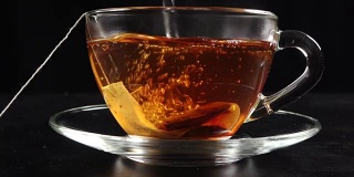 将茶叶倒入透明杯中，加入热水和茶包，动作缓慢