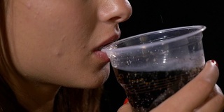 可爱女孩用塑料杯喝可乐汽水的慢动作