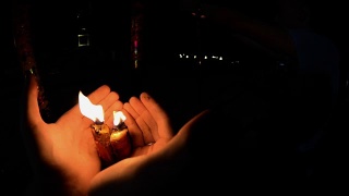 晚上在佛寺里点燃蜡烛。男人的手在火红的大蜡烛在寺庙gopro。中国庙里的红烛。第一人称射击。泰国的寺庙视频素材模板下载