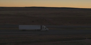在金色的日出，在繁忙的高速公路上运输货物的空中集装箱半挂车