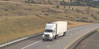空中近距离拍摄在美国大平原上运送货物的白色半卡车