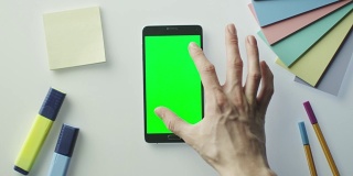 设计师正在使用Android手机与绿色屏幕在肖像模式。前视图。