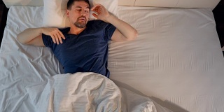 一个宿醉的男人在床上喝水。4 k。