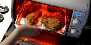 用手的动作把炸鸡放进烤箱