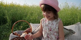 野餐自然，可爱的小女孩肖像吃百吉饼，生面团产品，喝牛奶在日落，孩子在家庭野餐