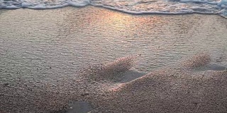 沙滩上的海浪在夕阳下的海洋海洋夏天的足迹