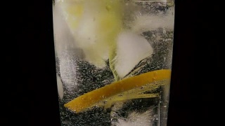 在装有苏打、冰和柠檬的玻璃杯中，滴下吸管。慢动作视频素材模板下载