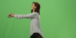 在背景的绿色屏幕上，一名女子正在推动一个虚拟的互动界面。