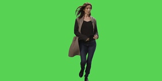 穿着外套的浅黑色女性在一个绿色屏幕模型的背景上奔跑。