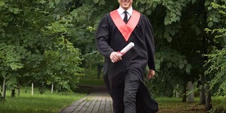 一名身穿学士服、手拿毕业证书、面带微笑的年轻人，高兴得跳了起来