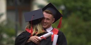 快乐的男人在毕业典礼上祝贺和拥抱年轻的女人，成就