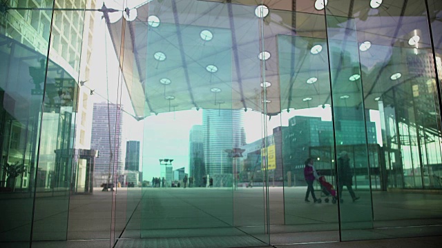 人们走在摩天大楼的创意玻璃入口附近，现代建筑