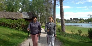 两个活跃的女人在公园里做北欧式散步。跟踪拍摄。慢动作