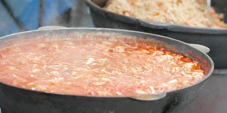 食物在铸铁锅里，志愿者在柴炉上准备饭菜，难民营，为乞丐准备热汤