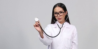 美丽的亚洲晒黑皮肤女医生白色衬衫西装与听诊器在颈部和检查听心脏脉搏姿势
