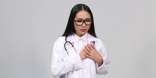 美丽的亚洲晒黑皮肤的女人医生白色衬衫西装与听诊器在颈部行走和得到心脏附落