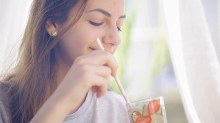 年轻女子喝黄瓜草莓排毒水。视频素材模板下载