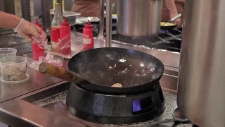 厨师在炉子上用火煎锅准备食物在大现代餐厅的厨房里视频素材模板下载
