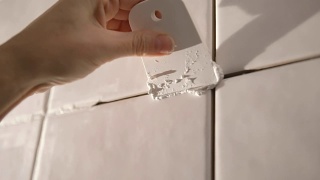 在浴室墙上贴瓷砖的工人。他的手把瓷砖放在粘合剂上视频素材模板下载
