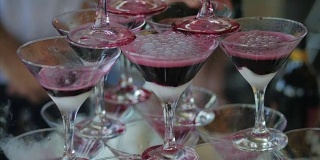 侍者将红酒或香槟酒倒入装有液氮的玻璃杯中。年轻人把酒杯里的酒倒进金字塔里