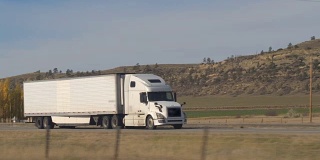 特写:白色半挂车拖着货物穿过美国乡村公路
